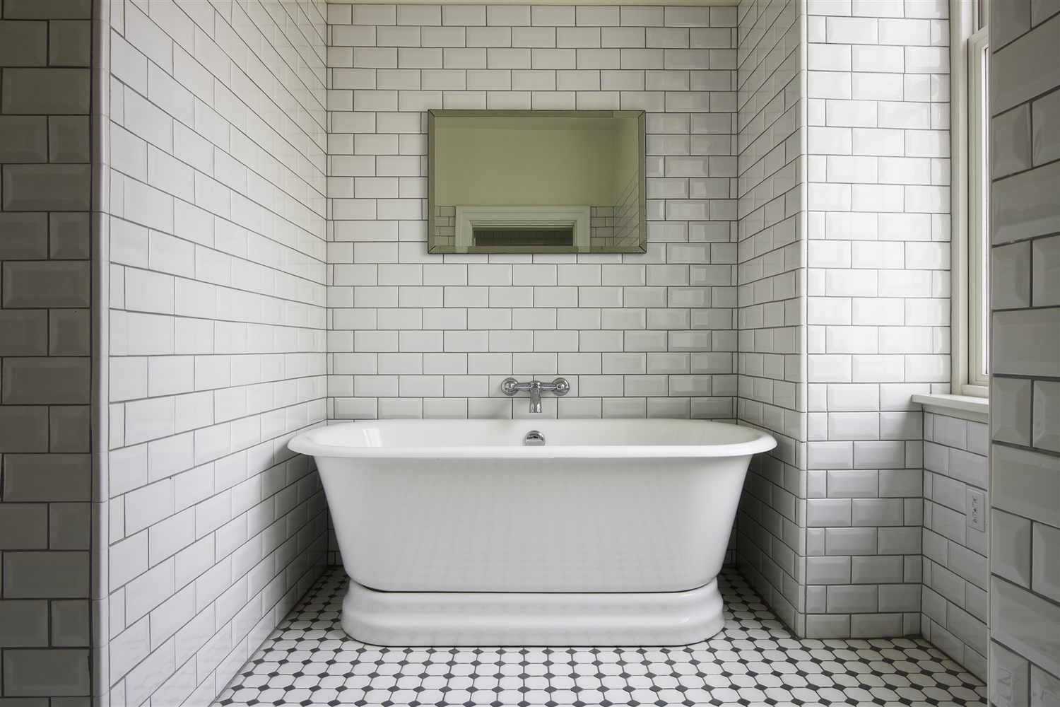 Pre-war style bathroom with white subway tile walls, a freestanding tub and a hexagon tile floor