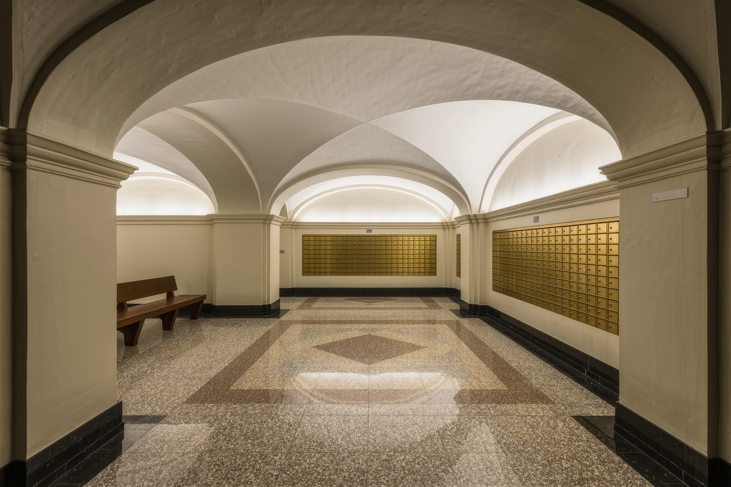 Lobby of a pre-war apartment building with a terrazzo floor, arched plaster ceiling and brass mailboxes