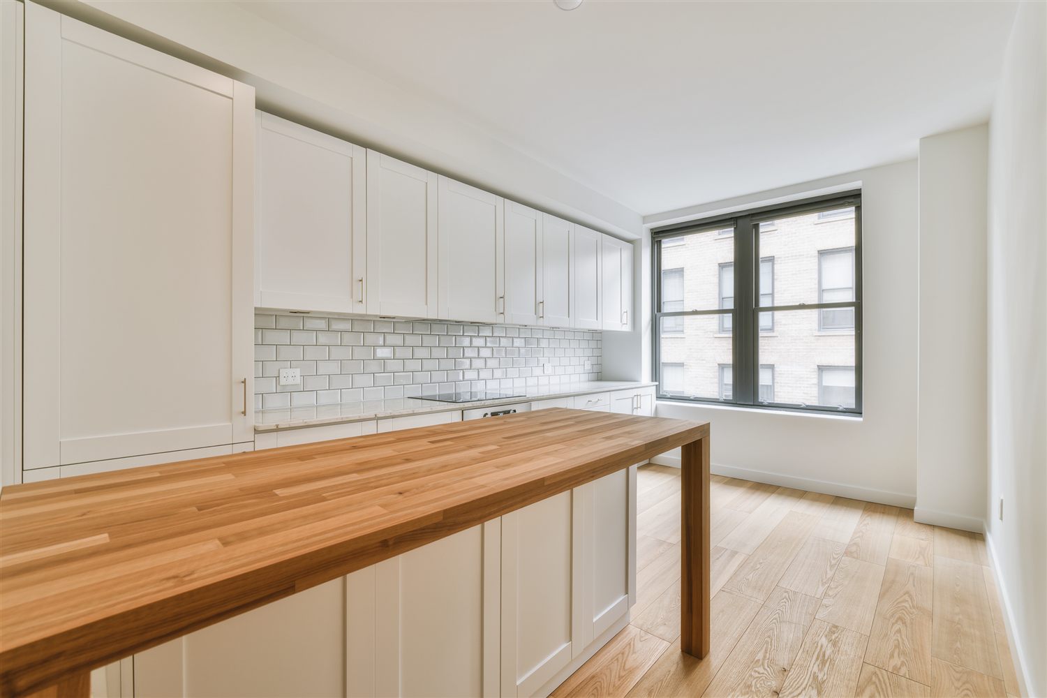 New kitchen with white shaker cabinets, subway tile backsplash and a butcher block counter beside a window